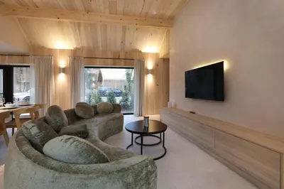 a living room with a couch and a flat screen tv at Villa Lodge met Jacuzzi - 8 personen - Woodz Lodges in Heusden - Zolder