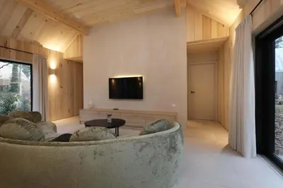 a living room with a couch and a tv on a wall at Villa Lodge met Jacuzzi - 8 personen - Woodz Lodges in Heusden - Zolder