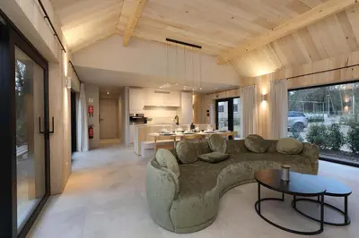 a living room with a couch and a kitchen at Villa Lodge met Jacuzzi - 8 personen - Woodz Lodges in Heusden - Zolder
