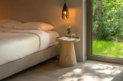 a bedroom with a bed with a table and a window at Suite Toegankelijk | 2 personen in Heusden - Zolder