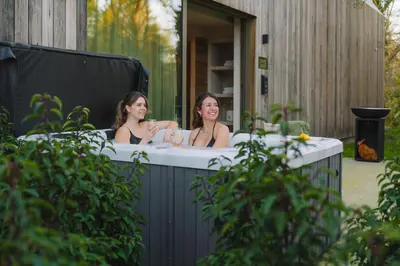 two women in a bathtub in a garden at Wellness Suite - 2 personen - Woodz Lodges in Heusden - Zolder