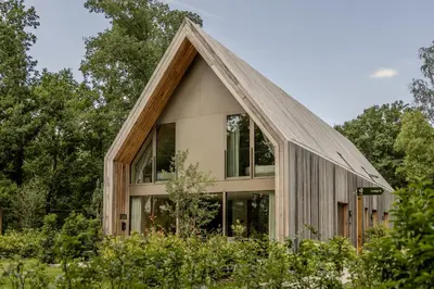 a house with a thatched roof and windows at Lodge - 8 personen - Woodz Lodges in Heusden - Zolder