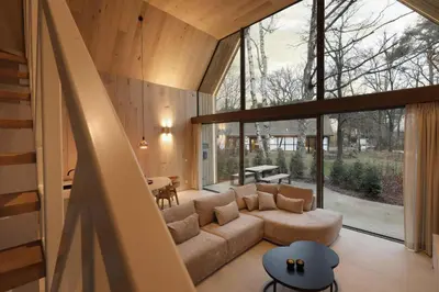 a living room with a couch and a large window at Lodge - 6 personen - Woodz Lodges in Heusden - Zolder