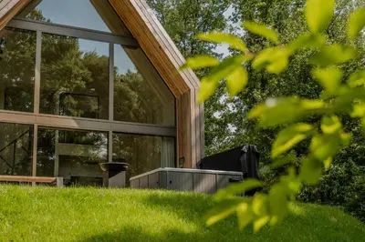 a glass house on a hill with green grass at Lodge met Jacuzzi - 6 personen - Woodz Lodges in Heusden - Zolder