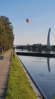 a kite flying over a river with a bridge at Casa Kanella Vakantiewoning in Maasmechelen