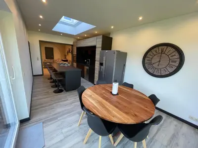 a dining room with a wooden table and a clock on the wall at Au 11801 Bel appartement moderne in Loncin
