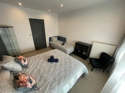 a bedroom with two beds and a chair at Au 11801 Bel appartement moderne in Loncin