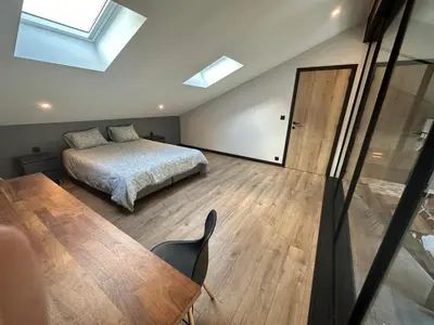a bedroom with a bed and a table and a window at Au 171 Le loft avec un sauna in Flémalle-Grande