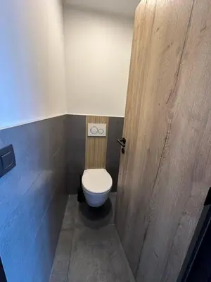 a bathroom with a toilet and a wooden door at Au 171 Le loft avec un sauna in Flémalle-Grande