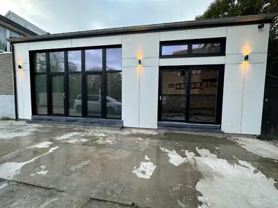 a white garage with glass doors on a driveway at Au 171 Le loft avec un sauna in Flémalle-Grande