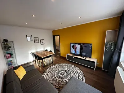 a living room with a couch and a table and a tv at Au 11811 Bel appartement cosy in Loncin