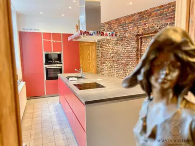 a kitchen with red cabinets and a statue of a girl at La maison de Maître - Grand Jardin, Face à la Meuse in Hermalle-sous-Argenteau