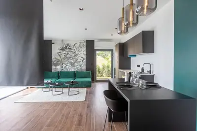 a living room with a green couch and a kitchen at le Bellessa Gite de luxe pour 2 personnes in Basse Tribomont