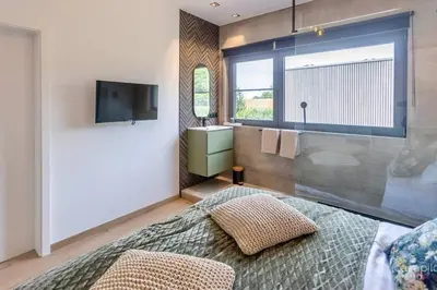 a bedroom with a bed and a television and a sink at Lodge 4 you gite de luxe pour 4 personnes in Verviers
