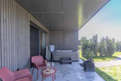 a patio with a tub and two chairs and a table at Gite Olea de deux personnes in Basse Tribomont
