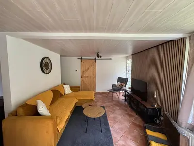 a living room with a couch and a television at Vakantiehuis chaletje in Lanaken