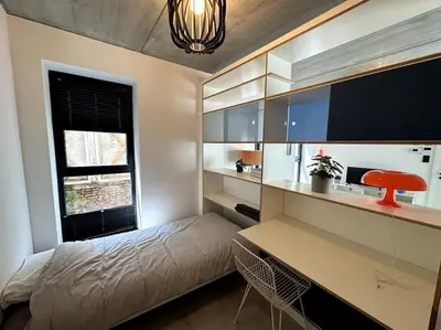a bedroom with a bed and a desk and a window at lOFT 202 in Liège