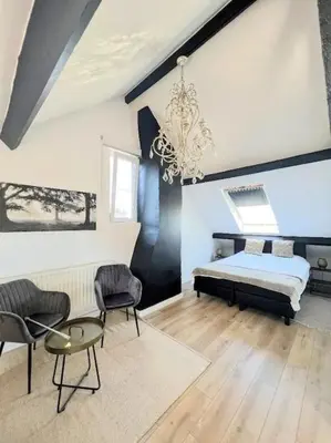 a bedroom with a bed and two chairs and a chandelier at Vakantiewoning De Merode in Lanaken