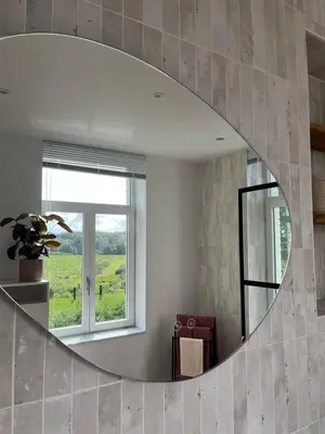 a circular mirror in a room with a window at Vakantiewoning de Toren in Kortessem