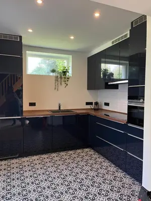 a kitchen with black cabinets and a tile floor at Vakantiewoning de Toren in Kortessem