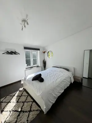 a white bedroom with a bed and a window at Lovely loft for romantic getaway or family trip in Chaudfontaine