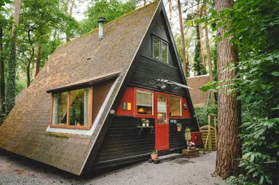 a tiny house in the woods with a red door at Boshuisje Rekem - Memories in Lanaken