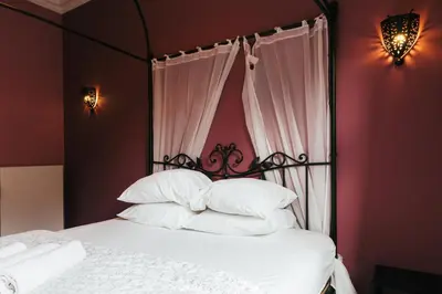 a bedroom with a bed with a black frame and white pillows at Hotel Riad Nour in Liège