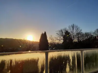 a sunset over a fence with the sun in the background at Atelier 27, Duplex with terrace and beautiful view in Liège