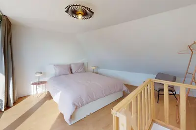 a white bedroom with a bed and a stair case at House W 35 in Liège