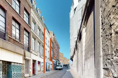 an empty street in an old city with buildings at House W 35 in Liège