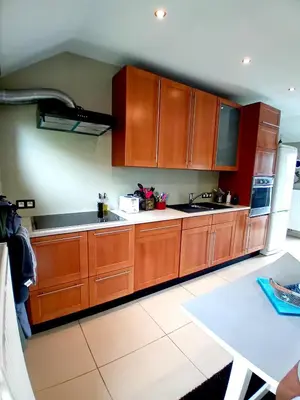 a kitchen with wooden cabinets and a white table at Le coin des évasions in Verviers
