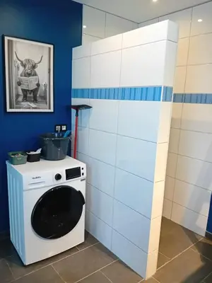 a washer and dryer in a blue and white kitchen at Le coin des évasions in Verviers