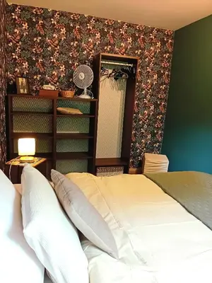 a bedroom with a bed and a floral wall at Le coin des évasions in Verviers