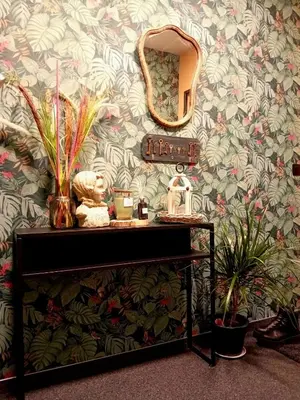 a dressing table with a mirror on a floral wall at Le coin des évasions in Verviers