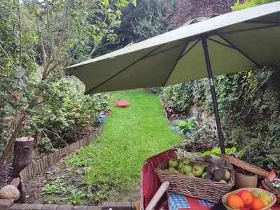 a table with an umbrella and a basket of fruit at Chez Marie in Liège