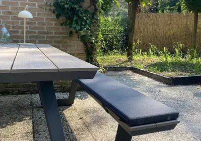 a picnic table with a bench next to a brick wall at Eekhoorn-huisje, 4-pers bungalow, Rekem in Lanaken