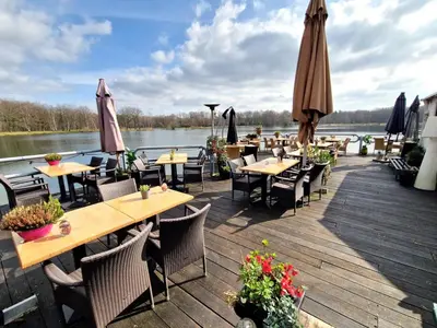 a restaurant with tables and umbrellas on a wooden deck at Eekhoorn-huisje, 4-pers bungalow, Rekem in Lanaken
