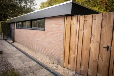 a building with a wooden fence and a brick wall at Wellnesshuisje Pocono cabin in Lanaken