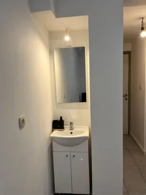 a white bathroom with a sink and a mirror at Superbe studio à Liège in Saint-Léonard