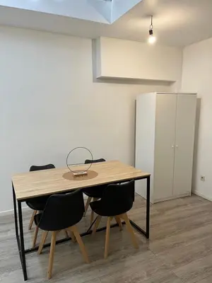 a dining room table with chairs and a refrigerator at Superbe studio à Liège in Saint-Léonard