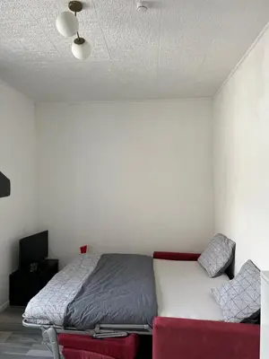 a bedroom with a bed and a red chair at Superbe studio calme et cosy in Saint-Léonard