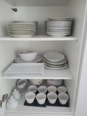 a white cabinet filled with dishes and plates at La grange aux anneaux in Beaurieux