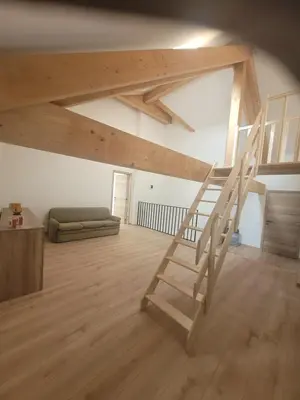 a loft with a wooden staircase in a room at La grange aux anneaux in Beaurieux