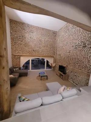 a living room with a couch and a brick wall at La grange aux anneaux in Beaurieux