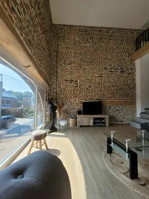 a living room with a brick wall and a couch at La grange aux anneaux in Beaurieux
