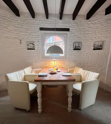 a dining room with a table and white chairs at Petit Château in Eupen