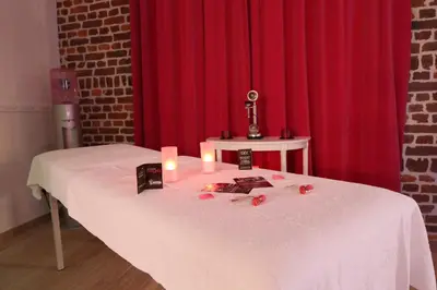 a table with candles and flowers on it with a red curtain at Studio Le Baiser d'Angeli in Ensival