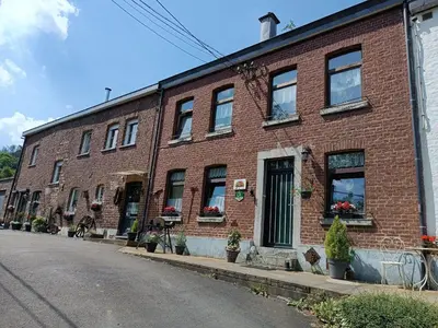 a red brick building with windows on a street at B&B Ferme du Petit Breuil in Verviers