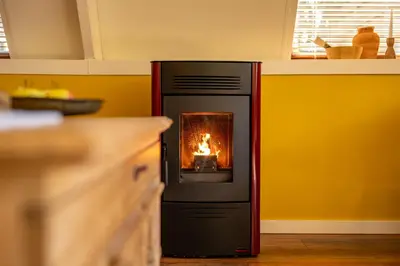 a stove in a kitchen with a fire in it at Boshuisje Rekem - Lotus in Lanaken
