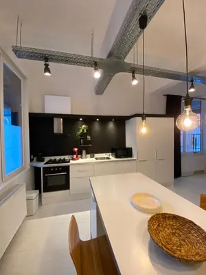 a kitchen with a white counter and a table at Loft St Remacle in Liège